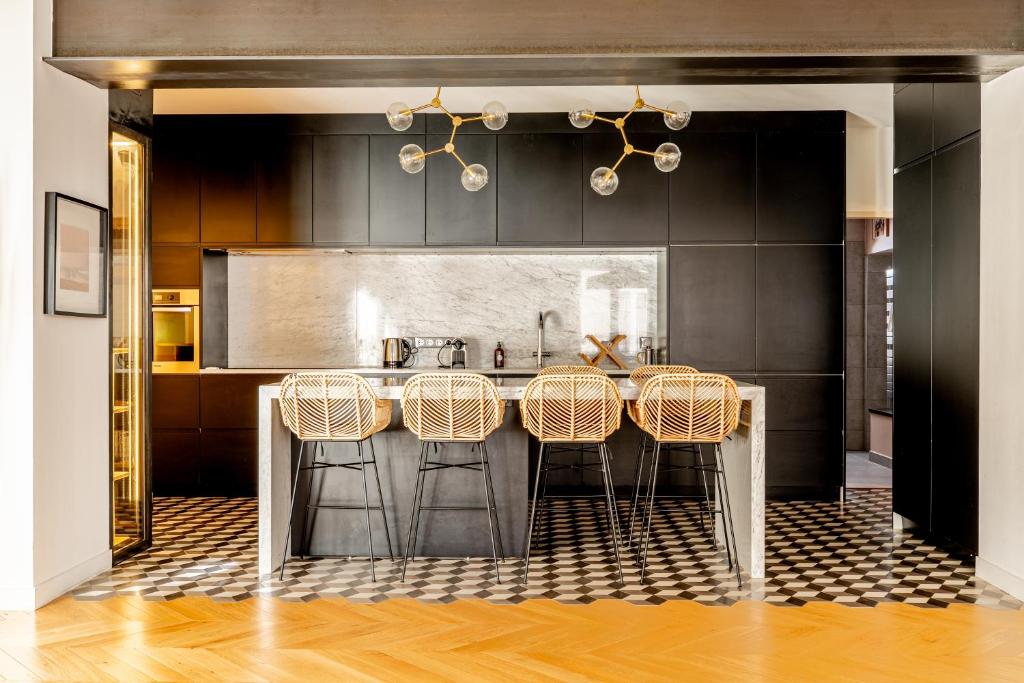 Kitchen — black cabinets, marble island, rattan bar stools