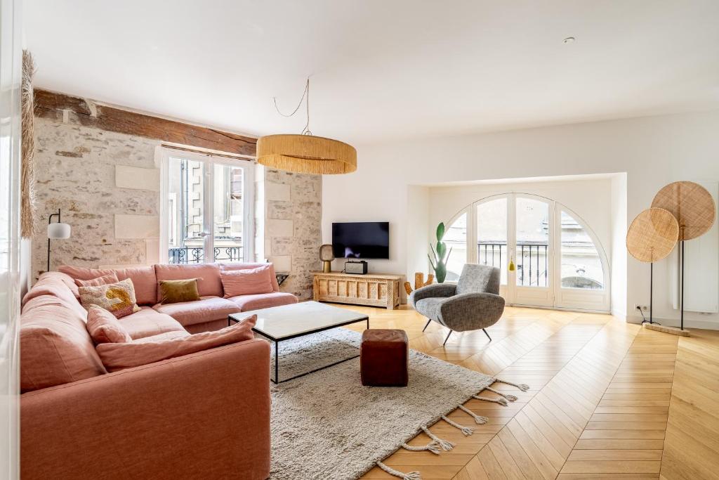 Living room — pink sofa, arched windows, stone wall, herringbone floors